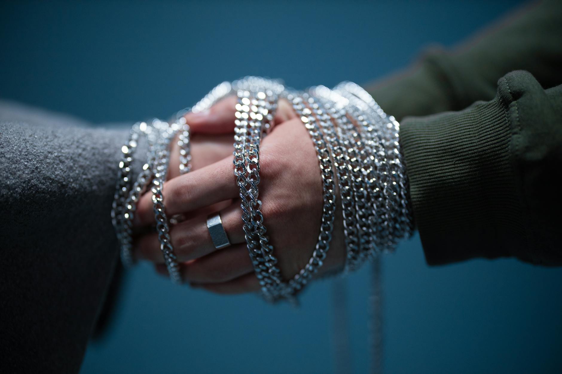 close up of hands of two people tied with a silver chain